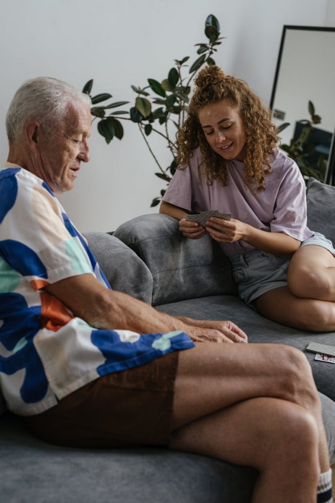 Man in White and Blue Shirt Sitting on Gray Sofa beside Woman in Purple Shirt